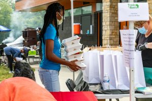 woman carrying stack of food takeout containers