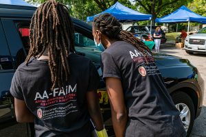 two woman speaking to a person through an open car window at an outdoor event