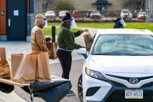 people handing paper bags through an open car window